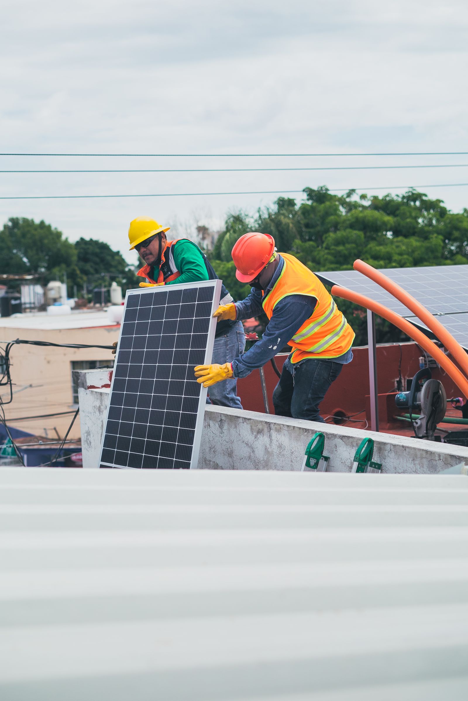 Two solar technicians carrying a panel; illustrative photography